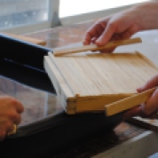 Demonstration of development in mould design. The woven screen gets moved to the top and is secured with deckle sticks.